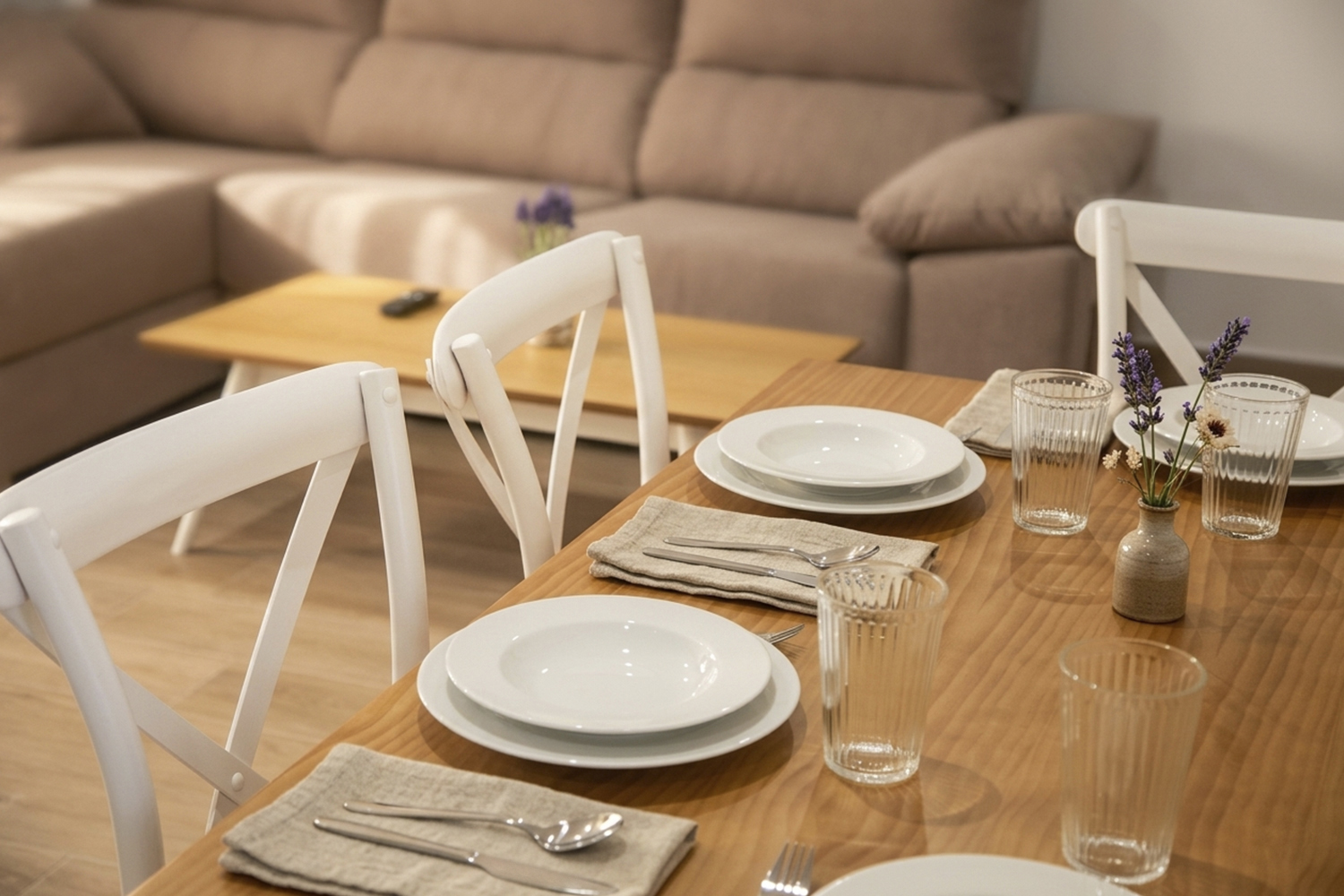 Comedor de apartamento rural en Puerto Lápice con mesa de madera, menaje completo y salón al fondo.