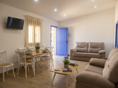Salón comedor moderno de apartamento rural en Puerto Lápice, con sofás, mesa de madera y TV.