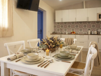 Salón comedor con mesa puesta y cocina equipada en apartamento rural de Puerto Lápice.