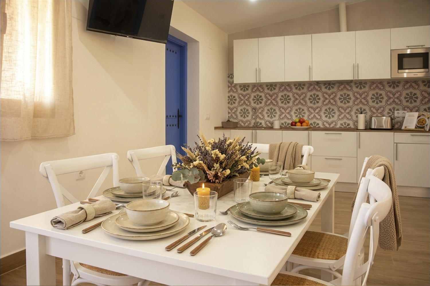 Salón comedor con mesa puesta y cocina equipada en apartamento rural de Puerto Lápice.