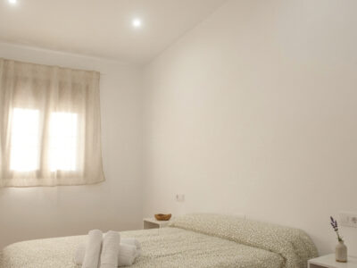 Habitación doble con decoración rústica y toallas blancas en posada de Puerto Lápice.